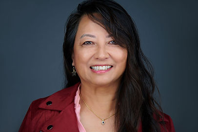 Asian woman with black hair, from the chest up wearing a maroon jacket and pink shirt