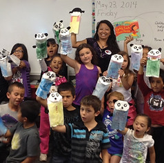 Natasha Yim with some students at a school visit holding up paper Goldy Luck and panda puppet craft